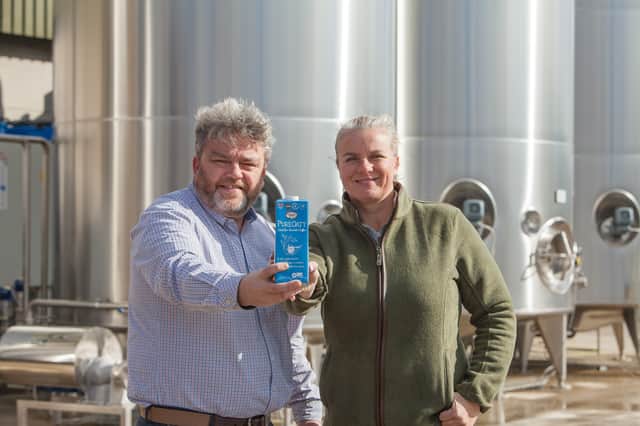 Philip and Rebecca Rayner of Glebe Farm Foods with a bottle of their PureOaty milk on their Cambridgeshire farm