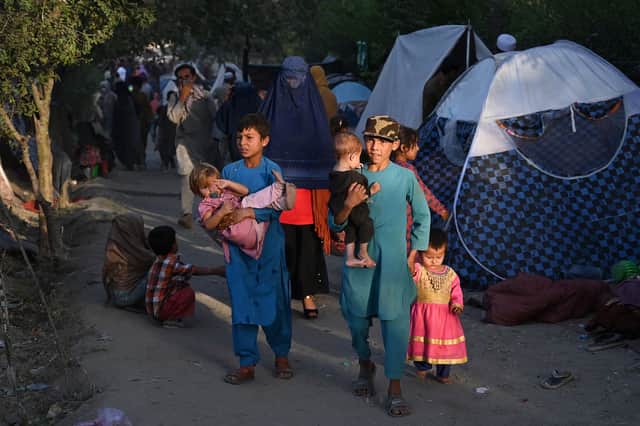 Internally displaced Afghan families, who fled from Kunduz, Takhar and Baghlan province due to battles between Taliban and Afghan security forces, walk past their temporary tents at Sara-e-Shamali in Kabul on August 11, 2021. (Photo by Wakil KOHSAR / AFP) 
