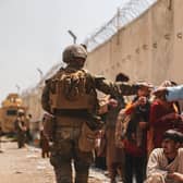 A US Marine passes water to evacuees during the evacuation at Hamid Karzai International Airport during the evacuation on August 21, 2021 in Kabul, Afghanistan. (Isaiah Campbell/U.S. Marine Corps/Getty)