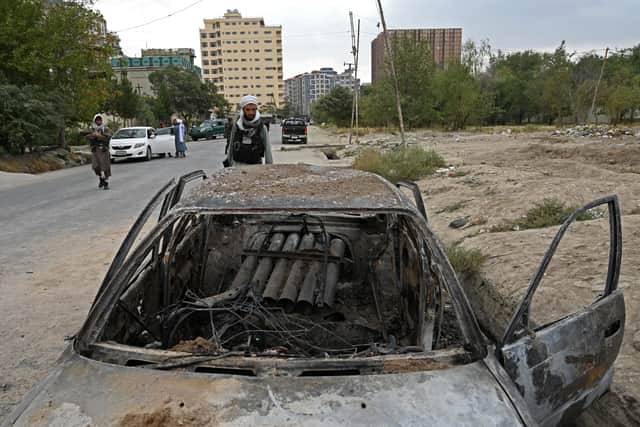 A Taliban fighter investigates a damaged car after multiple rockets were fired in Kabul on August 30, 2021 (Photo by WAKIL KOHSAR/AFP via Getty Images)
