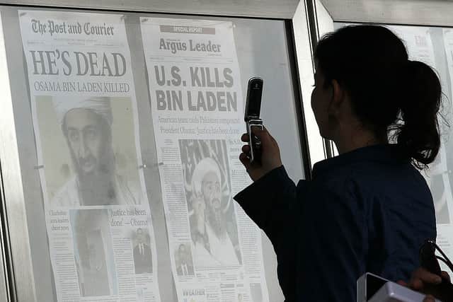 A passerby takes pictures of newspaper headlines reporting the death of Osama Bin Laden in May 2011 (Photo: Mark Wilson/Getty Images)