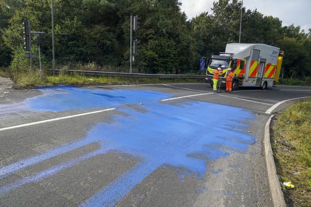 Highways England workers on the exit slip road of the M25 motorway near Leatherhead after protestors blocked the road and left paint on it (image: PA)