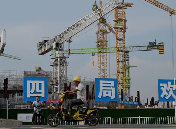 <p>Workers drive their motorbikes in front of the under-construction Guangzhou Evergrande football stadium in Guangzhou, China’s southern Guangdong province on September 17, 2021. (Pic: Getty)</p>
