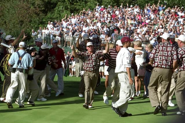 Justin Leonard of the USA tries to clear the celebrating American team off the green after sinking a long birdie putt on the 17th during the final day of the 33rd Ryder Cup 