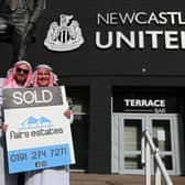 Newcastle United supporters dressed in robes pose with 'sold' placards as they celebrate the sale of the club to a Saudi-led consortium, outside the club's stadium at St James' Par