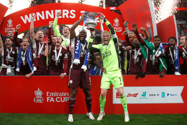 Kasper Schmeichel and Wes Morgan of Leicester City lift the Emirates FA Cup Trophy in celebration with team mates following The Emirates FA Cup Final match between Chelsea and Leicester City at Wembley Stadium on May 15, 2021