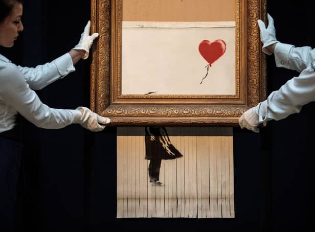 <p>Sotheby’s employees pose with ‘Love is in the Bin’ by British artist Banksy (Photo: Jack Taylor/Getty Images)</p>