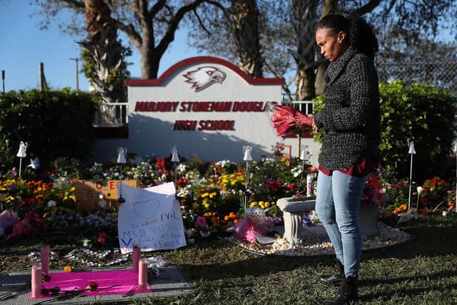 Sheena Billups prepares to lay flowers in a memorial setup at Marjory Stoneman Douglas High School for those killed during a mass shooting a year earlier (Photo: Joe Raedle/Getty Images)