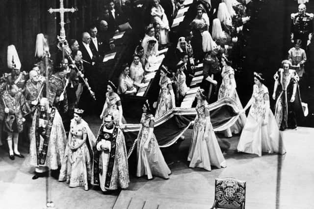 Queen Elizabeth II, surrounded by the bishop of Durham Lord Michael Ramsay (L) and the bishop of Bath and Wells Lord Harold Bradfield, walks to the altar during her coronation ceremony on June 02, 1953 in Westminster Abbey, London, as her maids of honour carry her train (Photo: -/INTERCONTINENTALE/AFP via Getty Images)