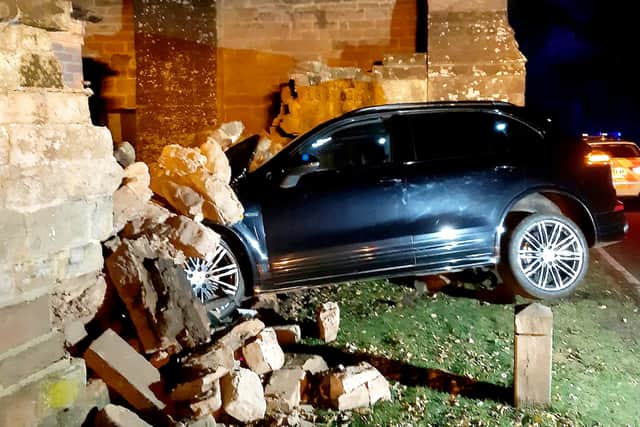 A Porsche driver cheated death after overshooting a junction and smashing into a historic stone gatehouse.