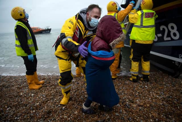 Migrants are helped ashore from a RNLI (Royal National Lifeboat Institution) lifeboat at a beach in Dungeness