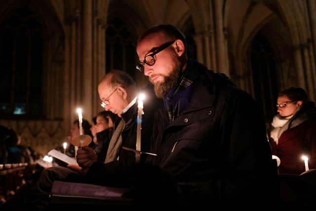 Members of the congregation hold candles and listen to the service during the Advent Procession (Photo by Ian Forsyth/Getty Images)