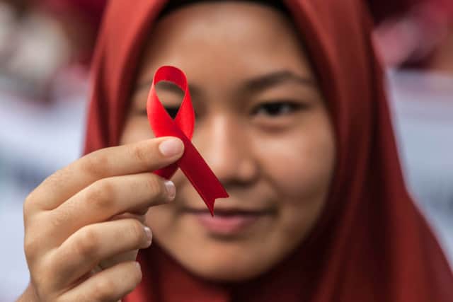 An Indonesian student holds a red ribbon as part of an awareness event on World AIDS Day (Photo: ALBERT IVAN DAMANIK/AFP via Getty Images)