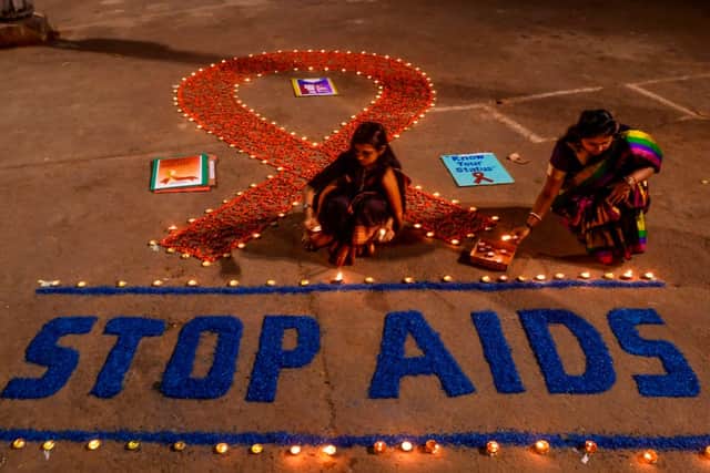 Volunteers light candles forming the shape of a red ribbon and a message reading ‘Stop AIDS’ during an awareness event on World AIDS Day (Photo: DIBYANGSHU SARKAR/AFP via Getty Images)