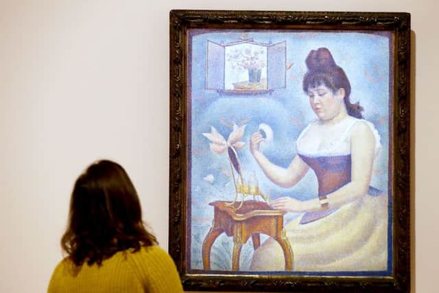 A visitor looks at the painting Jeune femme se poudrant by Georges Seurat (Photo: FRANCOIS GUILLOT/AFP via Getty Images)