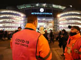 A Covid-19 spot checker is seen outside the stadium prior to the Premier League match between Manchester City and Leeds United. (Photo by Clive Brunskill/Getty Images)
