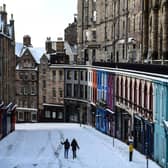 People walk in the snow on the deserted Victoria Street in Edinburgh in February this year. (Photo by ANDY BUCHANAN/AFP via Getty Images)