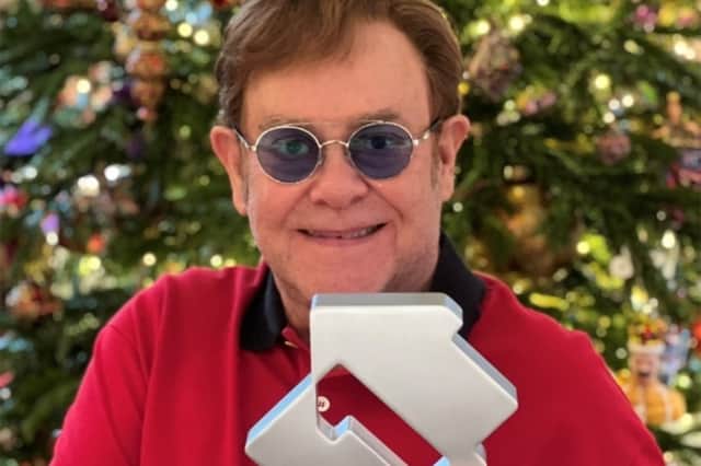 Christmas number one success give Elton John - pictured here at home in front of his Christmas tree - brings his career total to 10 chart toppers (Photo: Rocket Entertainment)