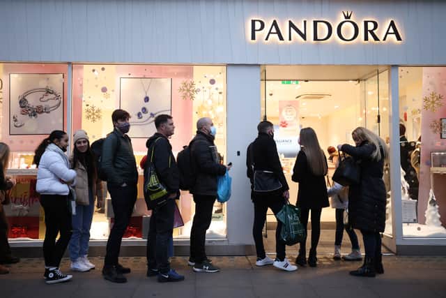 Shoppers queue up to enter a Pandora store in the West End on December 21, 2021 in London, England.
