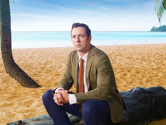 DI Neville Parker (Ralf Little) sat on a log on a beach (Credit: BBC / Red Planet / Amelia Troubridge)