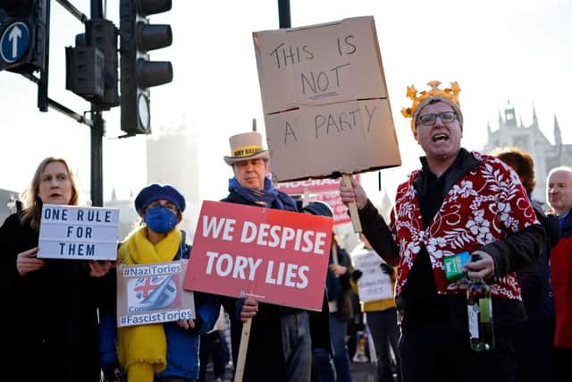 Demonstrators hold placards as they protest near the House of Commons, where Boris Johnson on Wednesday said sorry after admitting he attended a lockdown-breaching party in Downing Street (Photo: TOLGA AKMEN/AFP via Getty Images)