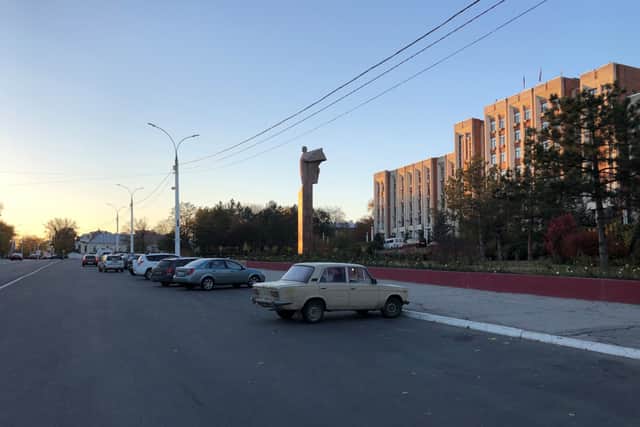 A Lada overshadowed by an angelic Lenin outside the Transnistrian parliament building