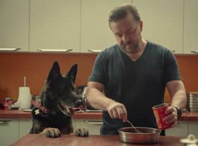 Ricky Gervais feeding dog Brandy (the dog is called Brandy, he’s not feeding brandy to the dog) (Credit: Natalie Seery/Netflix)