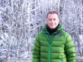 Chris Packham, wearing a green puffy coat, in a winter-y forest (Credit: BBC/Jo Charlesworth)