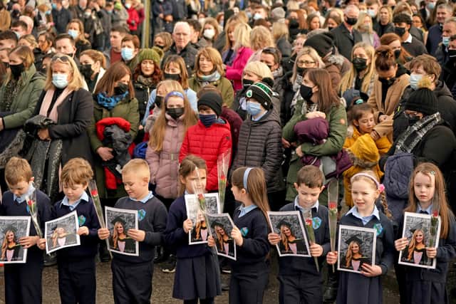 Pupils from Ashling Murphy’s class hold photographs of her and red roses outside St Brigid’s Church (image: PA)