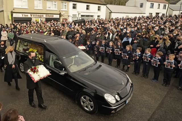 Schoolchildren taught by Ashling Murphy hold photographs of her as the cortege passes by on arrival at St Brigid’s Church, Mountbolus (image: PA)