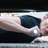 Vicky McClure lies flat on the ground, shining a torch to look under a car (Credit: Ross Ferguson/ITV)