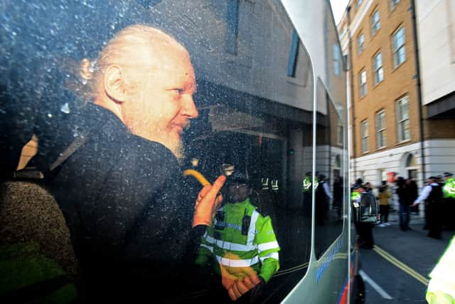 Julian Assange gestures to the media from a police vehicle (Photo: Jack Taylor/Getty Images)