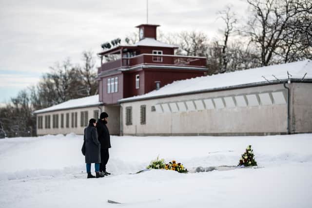 People stand in front of a commemorative plaque at the memorial site of the former Nazi concentration camp Buchenwald near Weimar, eastern Germany (Photo: JENS SCHLUETER/AFP via Getty Images)