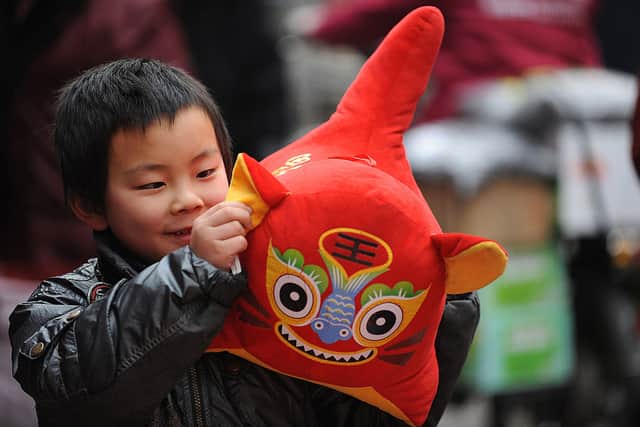 A young Chinese boy plays with  a toy tiger doll (Photo: STR/AFP via Getty Images)
