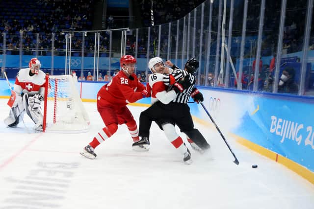 Raphael Diaz #16 of Team Switzerland collides with referee Maxim Sidorenko #19 of Belarus in the third perio during the Men's Preliminary Round Group B match on Day 5 of the Beijing 2022 Winter Olympic Games at National Indoor Stadium on February 09, 2022 in Beijing, China.