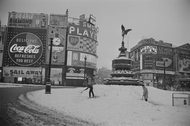 View of men using spades to shovel snow from around the Statue of Eros and Shaftesbury Memorial Fountain in the centre of Piccadilly Circus in London after heavy snowfall on 1st January 1963.
