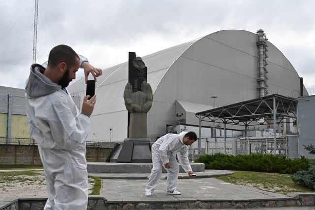 Tourists take pictures at the new metal dome encasing the destroyed reactor at the Chernobyl nuclear power plant in 2019 (Photo: GENYA SAVILOV/AFP via Getty Images)