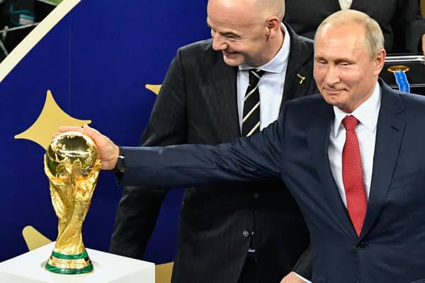 Russian President Vladimir Putin (R) caresses the trophy next to FIFA president Gianni Infantino (C) during the trophy ceremony at the end of the Russia 2018 World Cup final