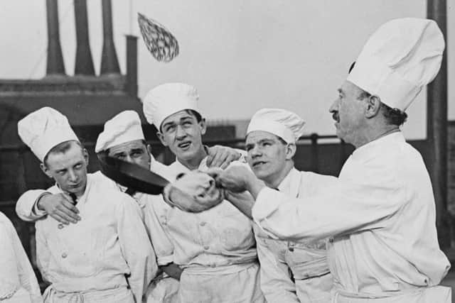 A group of trainee cooks from the London School of National Cookery watch an expert toss a pancake on Shrove Tuesday in 1933 (Photo by Fox Photos/Getty Images)