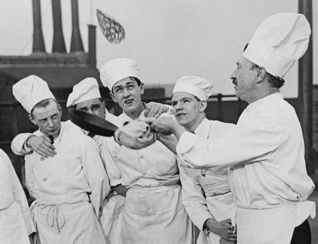 A group of trainee cooks from the London School of National Cookery watch an expert toss a pancake on Shrove Tuesday in 1933 (Photo by Fox Photos/Getty Images)