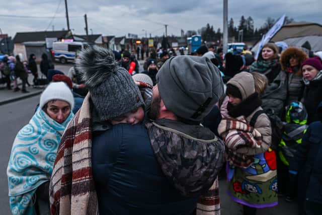 A man who fled the war in Ukraine holds a baby as they wait in line to board a bus (Photo by Omar Marques/Getty Images)