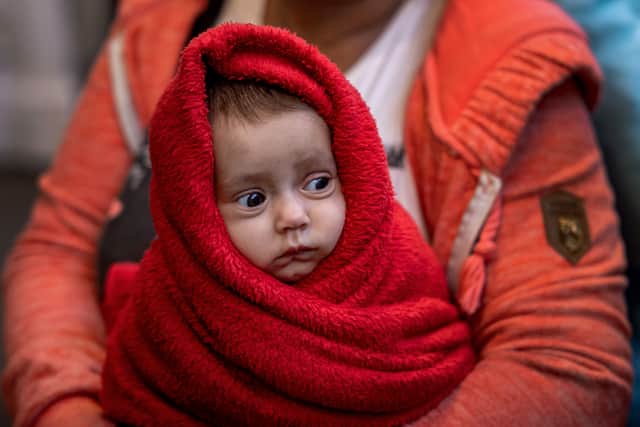 A Ukrainian woman holds her 3-month-old baby at the Western Railway Station as they flee Ukraine on March 9, 2022 in Budapest, Hungary (Photo by Janos Kummer/Getty Images)