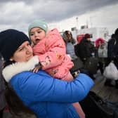 A woman holds a baby as she leaves among other refugees at the border point between Romania and Ukraine (Photo by DANIEL MIHAILESCU/AFP via Getty Images)