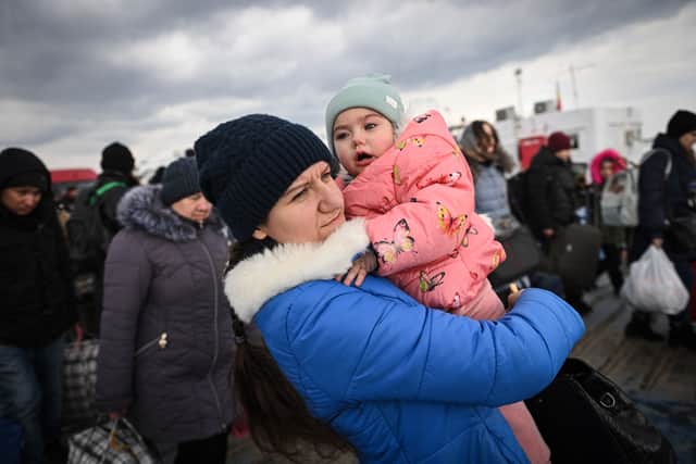 A woman holds a baby as she leaves among other refugees at the border point between Romania and Ukraine (Photo by DANIEL MIHAILESCU/AFP via Getty Images)