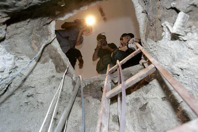 A Brazilian Federal Police agent (R) and journalists look through the tunnel dug by the Central Bank robbers