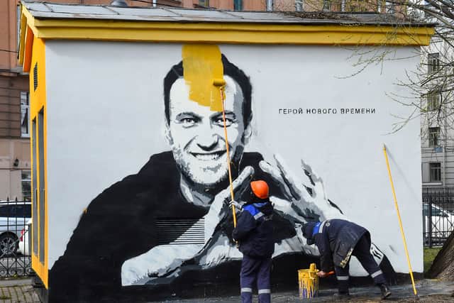 A worker paints over graffiti of jailed Kremlin critic Alexei Navalny in Saint Petersburg on April 28, 2021. The inscription reads: "The hero of the new times". 