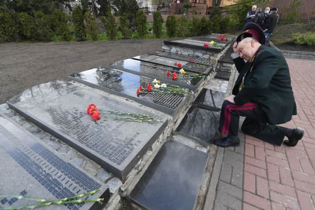 A liquidator of Chernobyl nuclear power plant kneels to pay his respects at Chernobyl’s memorial (Photo by SERGEI SUPINSKY/AFP via Getty Images)