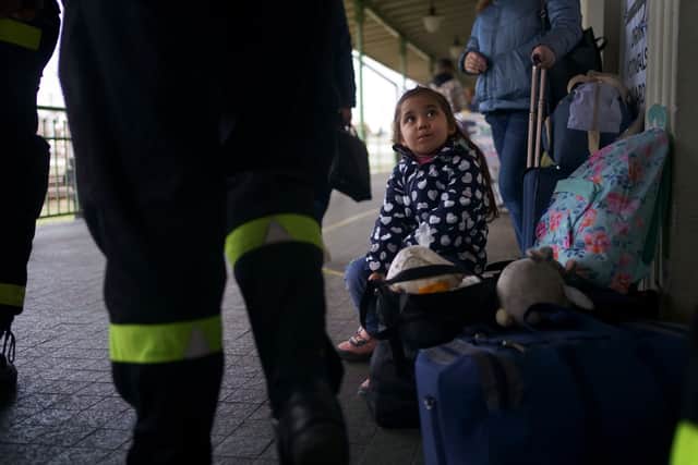 A young Ukrainian refugee looks up at guards on a platform at Przemysl Glowny train station in Poland after arriving with her family to flee the Russian invasion.