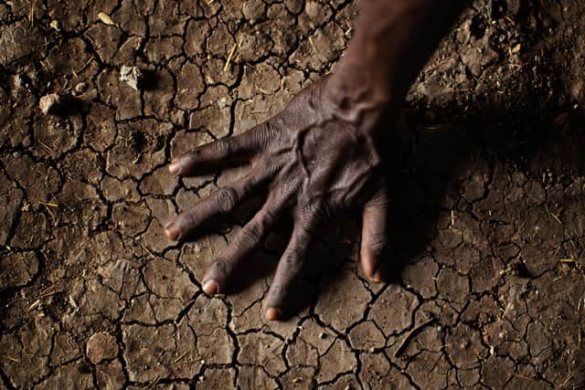 A man places his hand on the parched soil in the Greater Upper Nile region of north-eastern South Sudan, Africa, as a major new UN report setting out the action needed to tackle the climate crisis is set to be released after marathon talks to agree its findings.