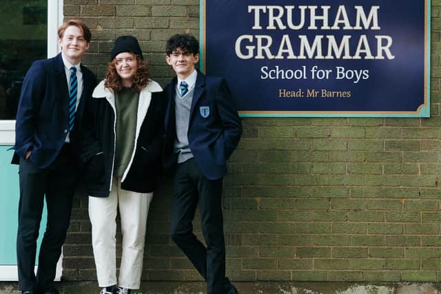 Kit Connor, Alice Oseman, and Joe Locke standing by the Truham Grammar School for Boys sign (Credit: Rob Youngson)
